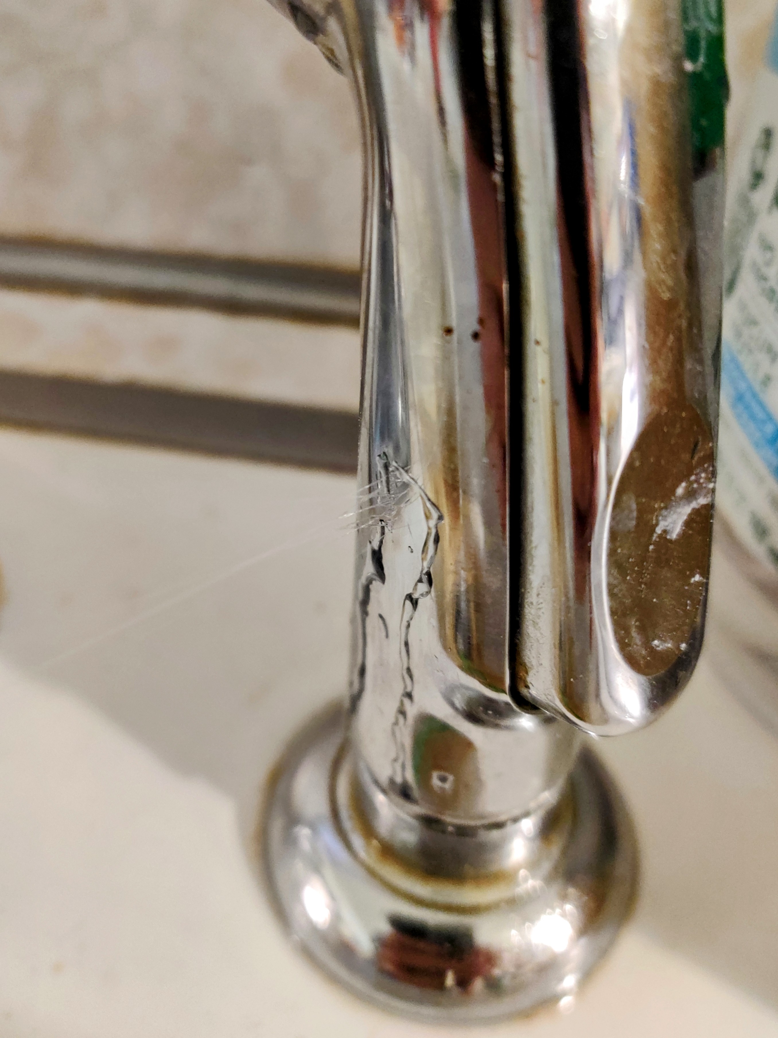 Close up of a side sprayer from a kitchen sink with a fast stream of water leaking from its side.